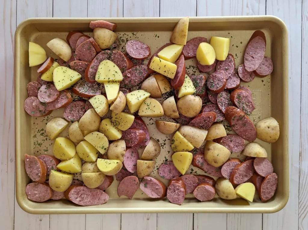 Kielbasa and potatoes on a rimmed baking sheet.