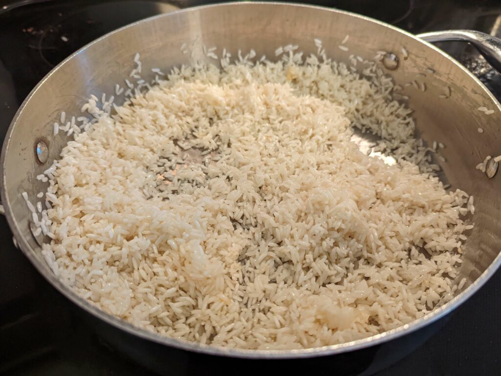 Rice toasting in oil in a pan.