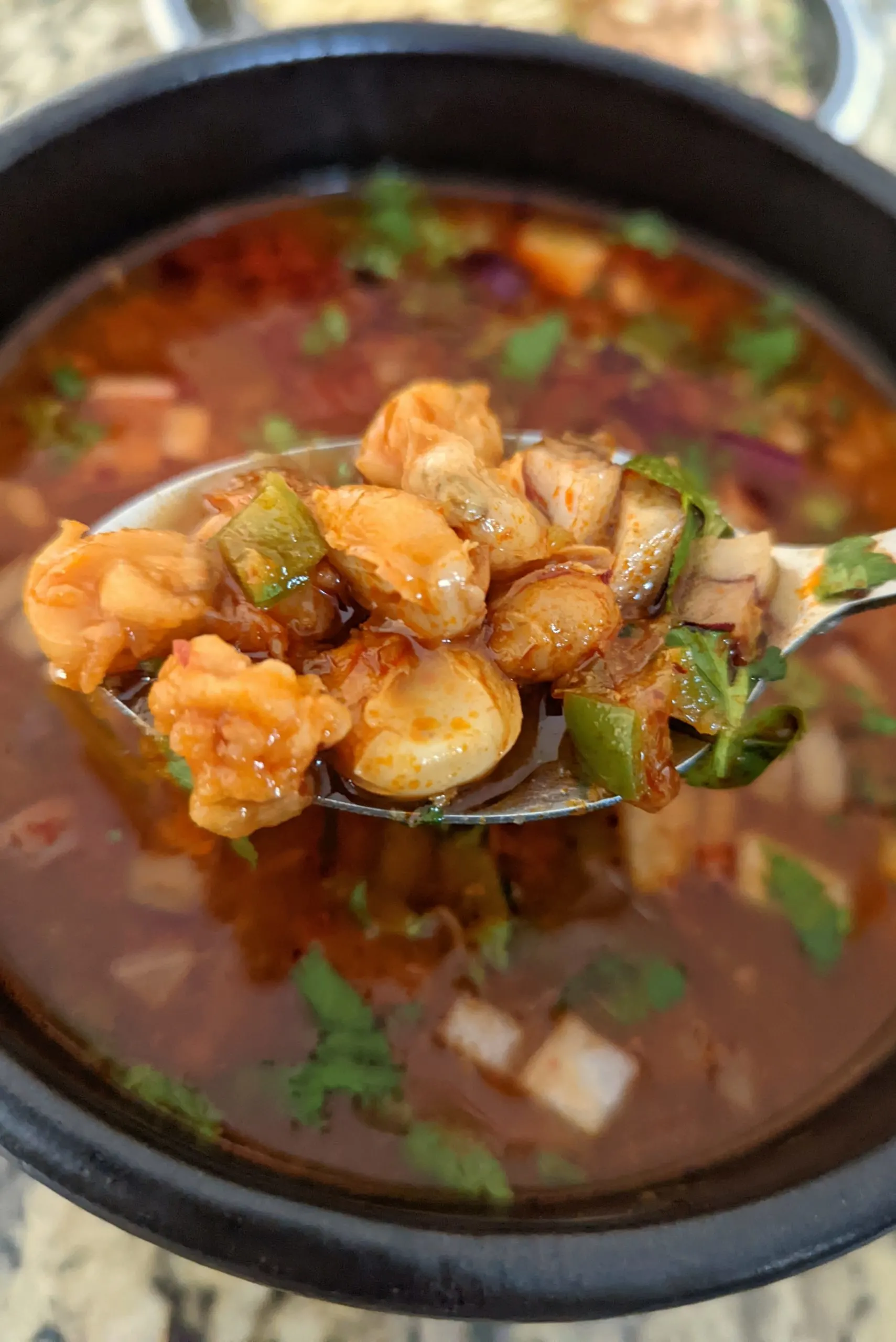 A close up of a spoonful of Instant Pot Pozole Rojo over the bowl.