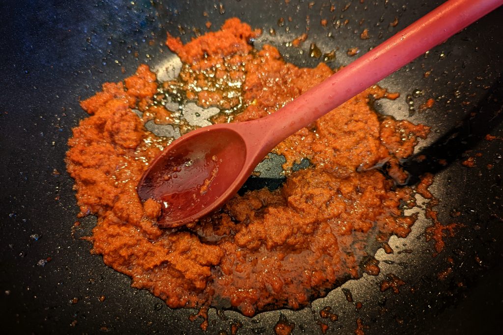 coconut oil and panang curry paste cooking in a pan.