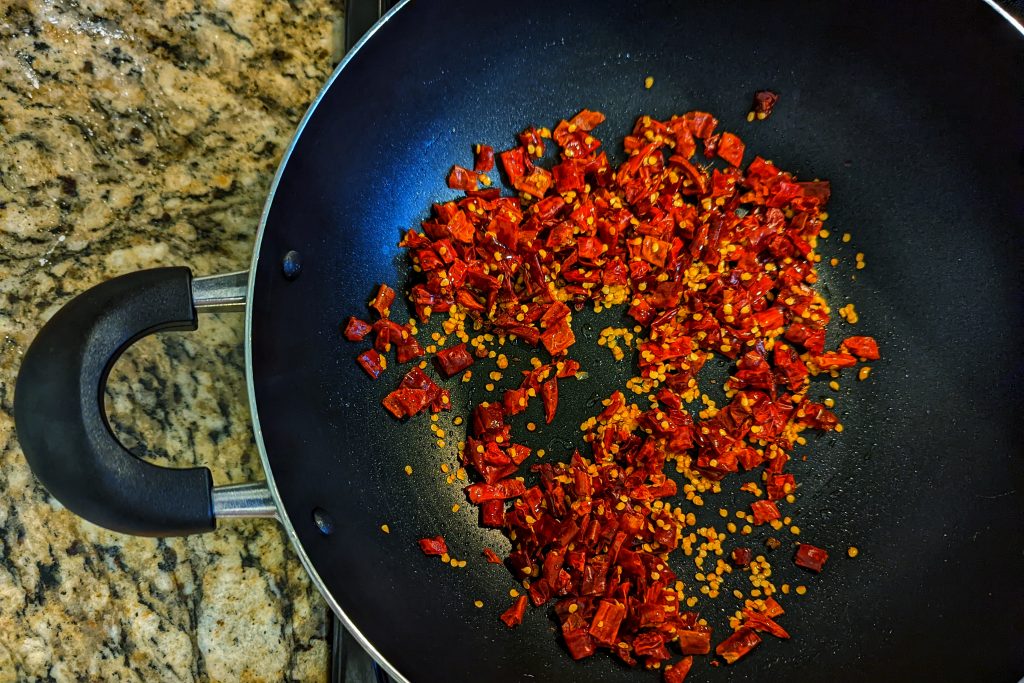 The base for the Sichuan fried chicken sauce is heated Sichuan peppercorns and arbol chilies.