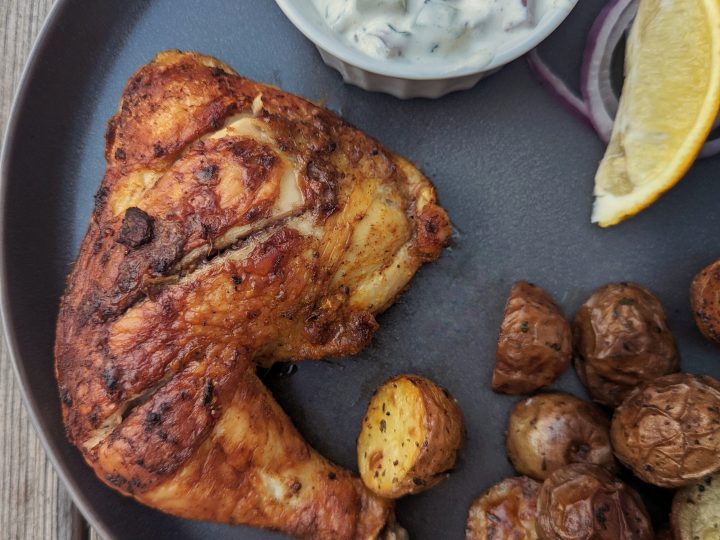 A serving of our baked tandoori chicken recipe served with raita and roasted potatoes.