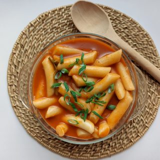 A large bowl of tteokbokki garnished with scallions and ready to serve.