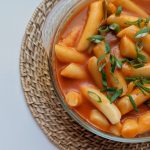 A large bowl of tteokbokki garnished with scallions and ready to serve.