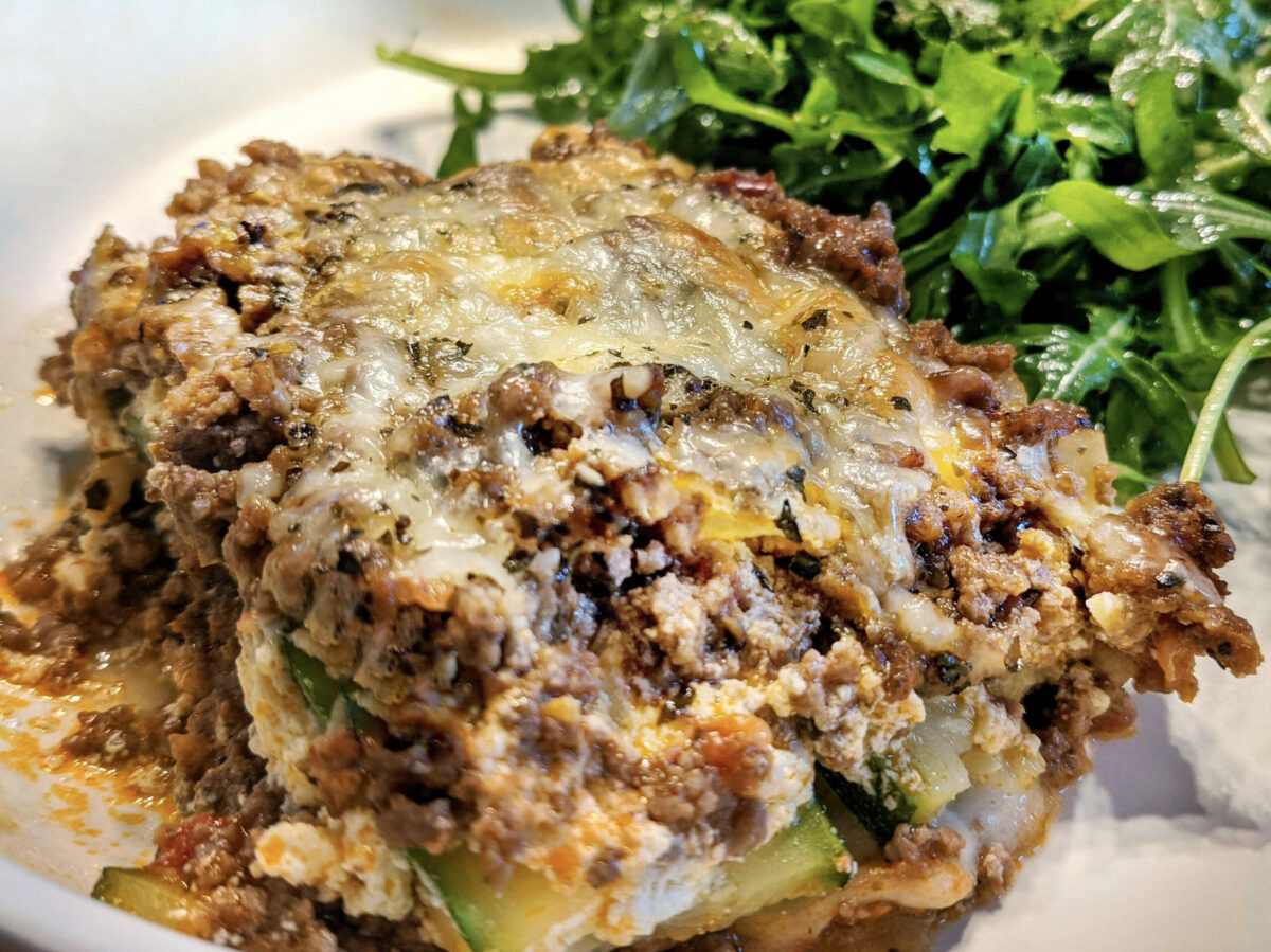 A heaping serving of zucchini lasagna served with an arugula salad.