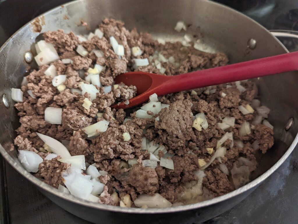 Ground beef, onions, and garlic sautéing in a pan.