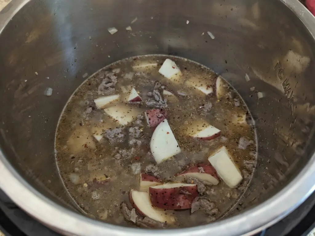 Potatoes and ground beef in a pot.