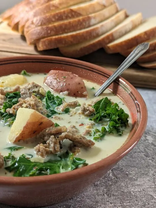 Zuppa Toscana Instant Pot in a bowl with bread in the background.