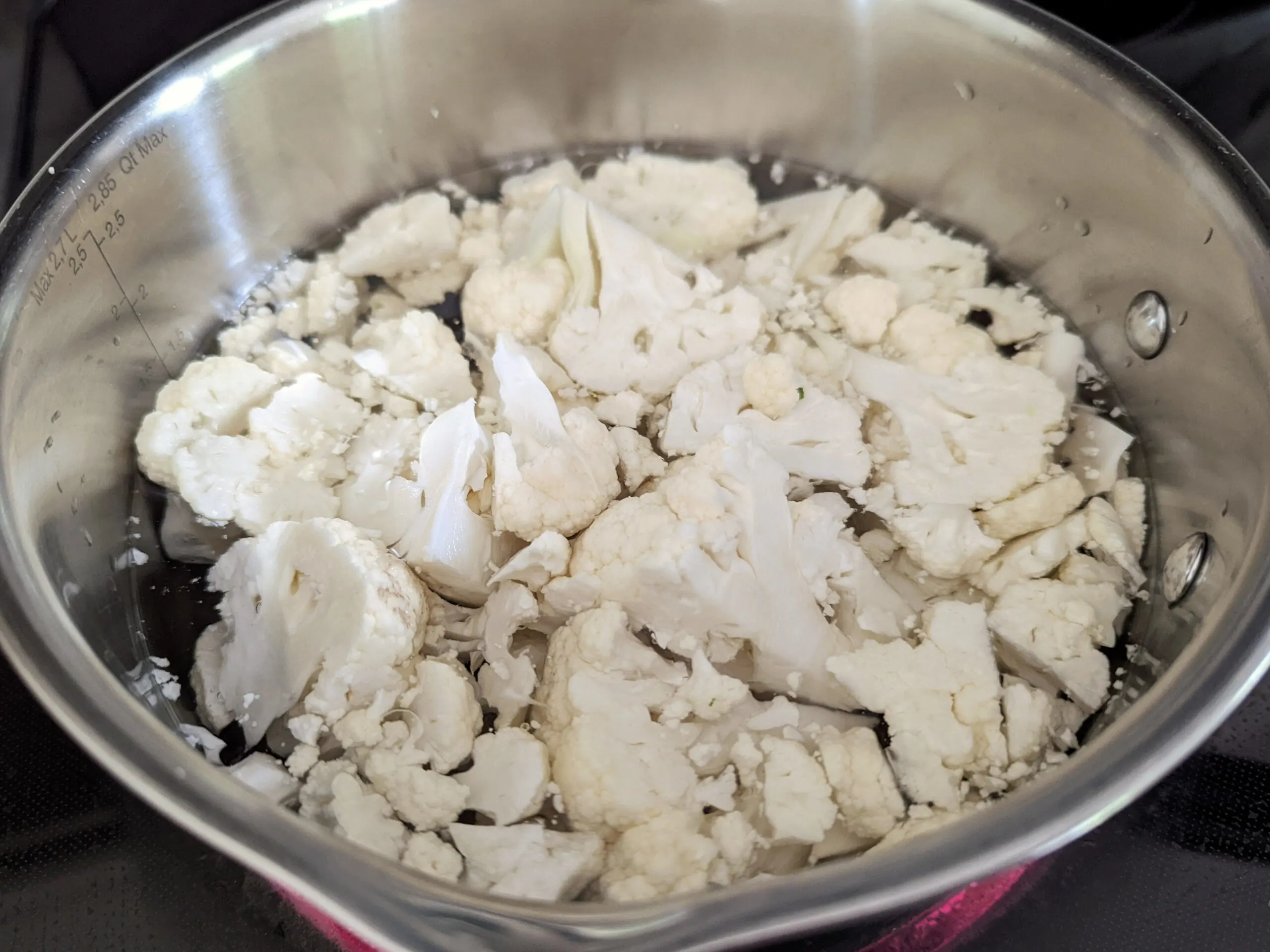 Begin by breaking down a cauliflower head and boil the smaller pieces until they are tender.