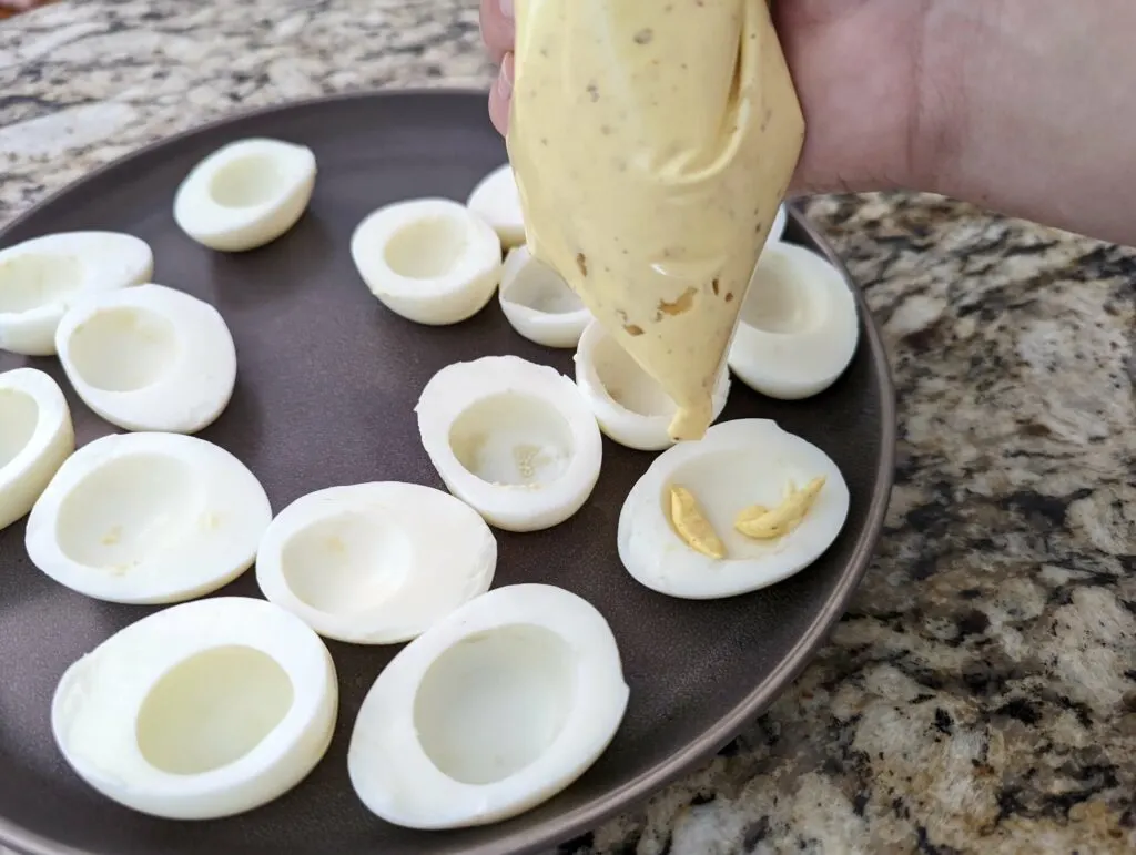 Filling for the deviled eggs in a piping bag and added to the emptied egg whites.