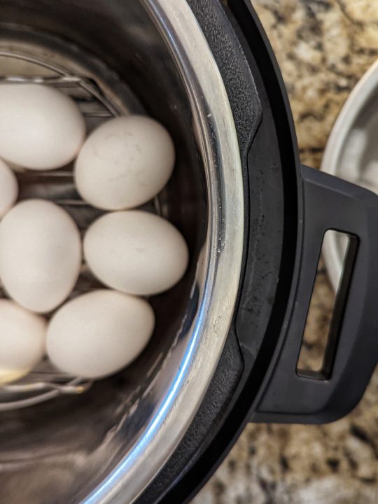 Fill an Instant Pot with one cup of water, add a trivet and add the hard boiled eggs.