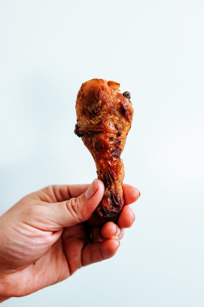 A hand holding a chicken drumstick.