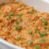 A close up of a serving bowl of Instant Pot Buffalo Chicken Dip topped with thinly sliced green onions.