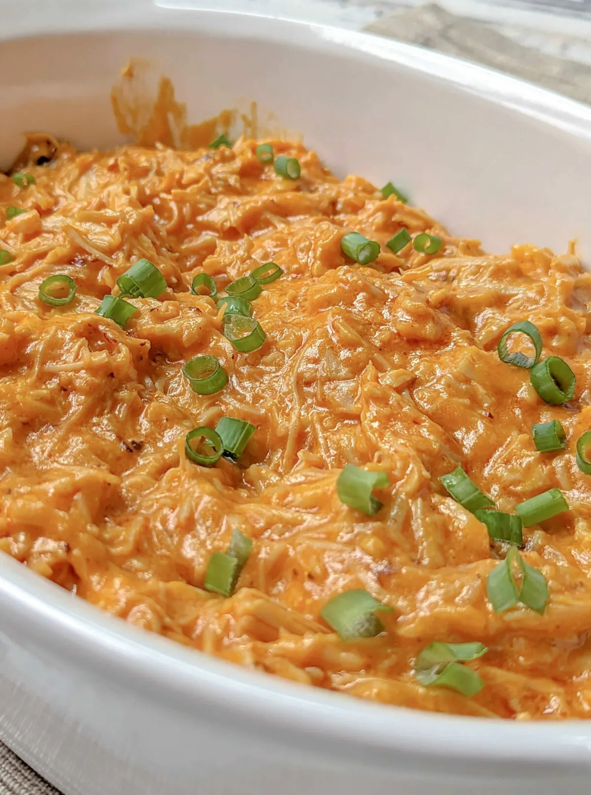 A close up of a serving bowl of Instant Pot Buffalo Chicken Dip topped with thinly sliced green onions.