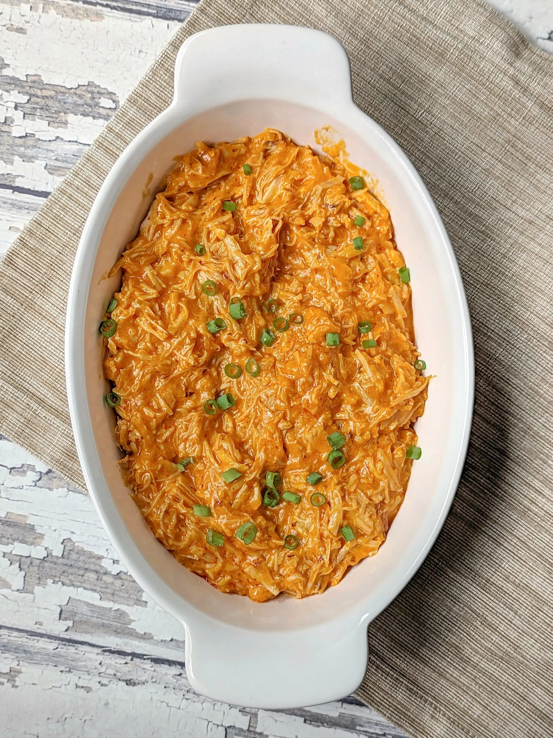 A serving bowl of Instant Pot Buffalo Chicken Dip topped with thinly sliced green onions.