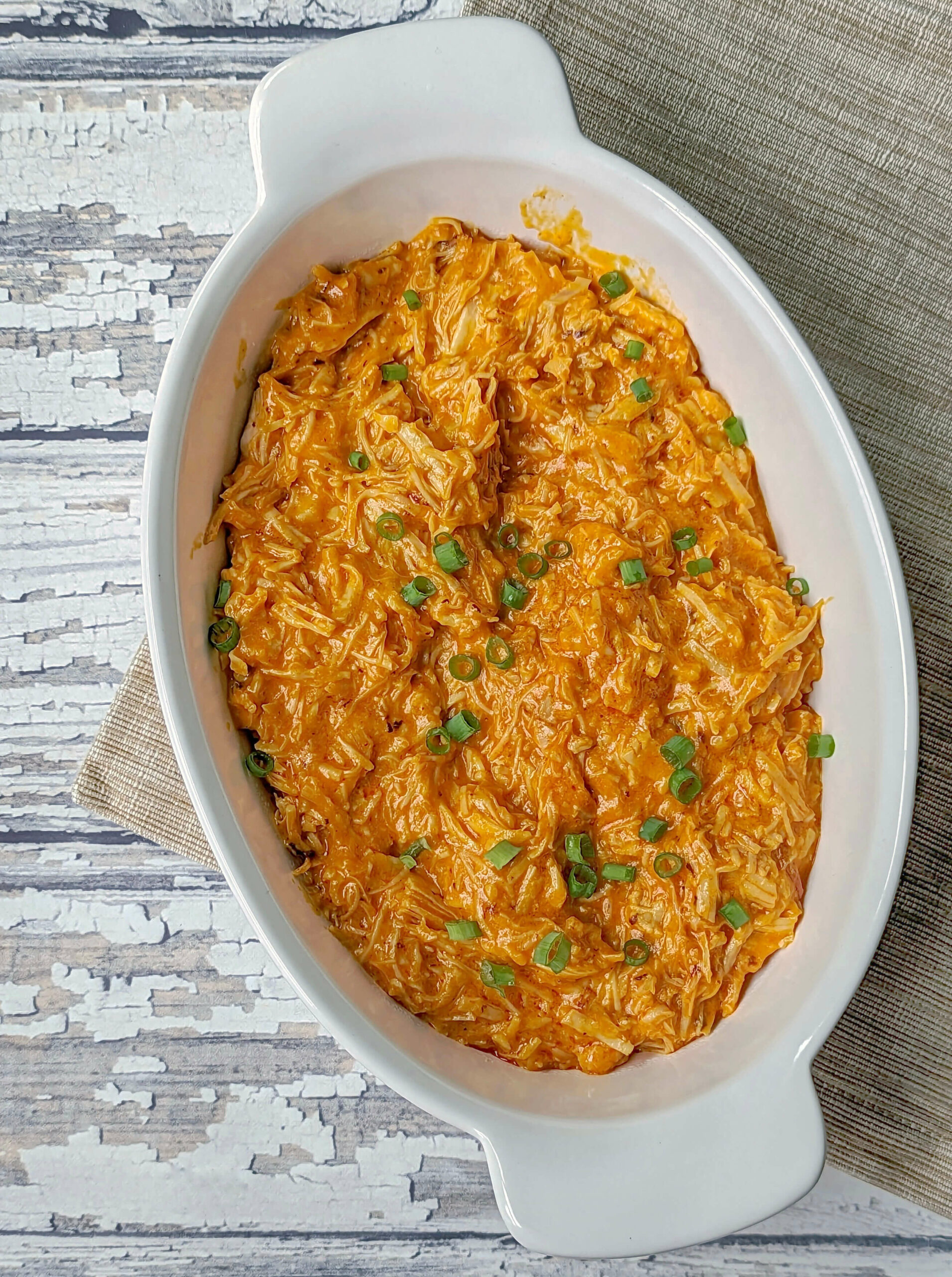 A serving bowl of Instant Pot Buffalo Chicken Dip topped with thinly sliced green onions.