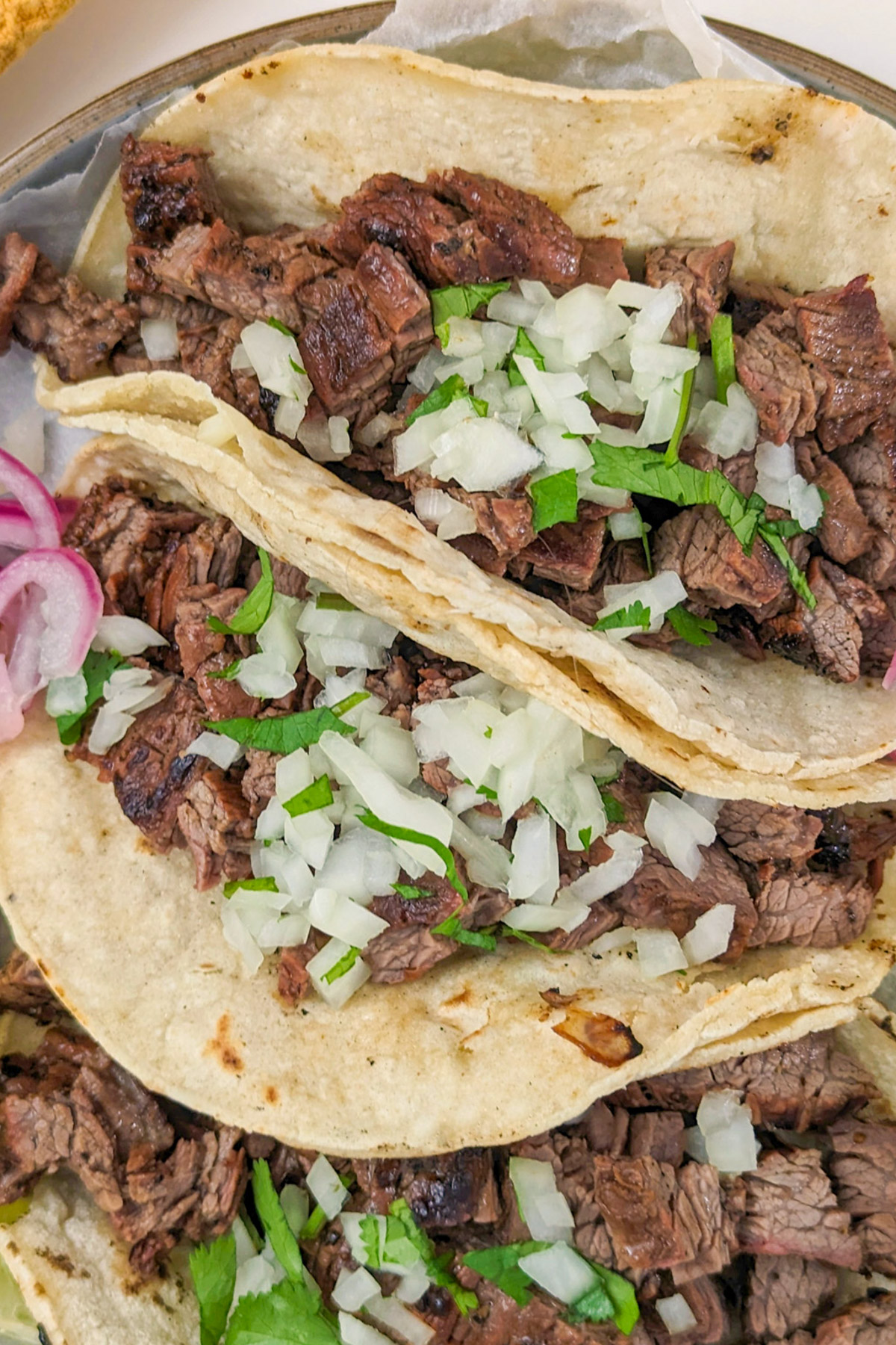 Three carne asada tacos with toppings.