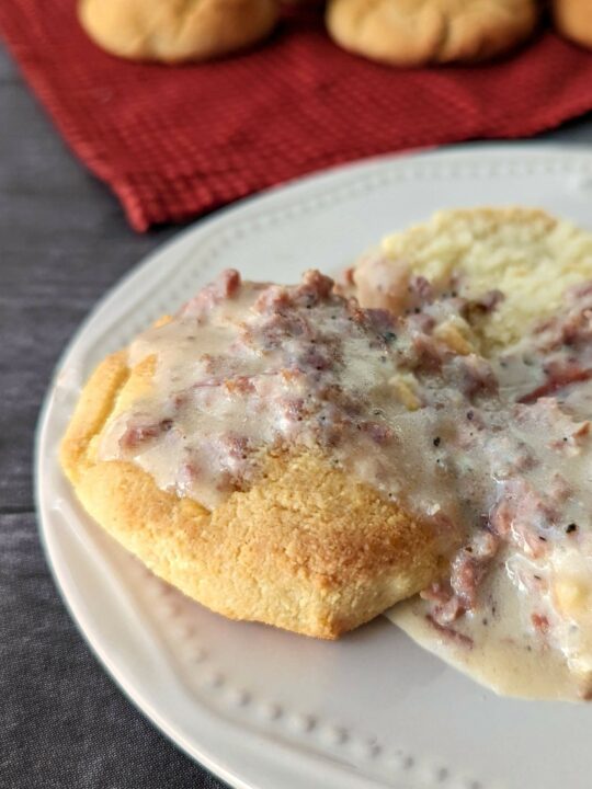 Keto biscuits and gravy in the foreground with biscuits in the background.h