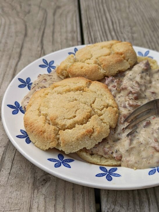 Keto biscuits and gravy in the foreground with biscuits in the background.h