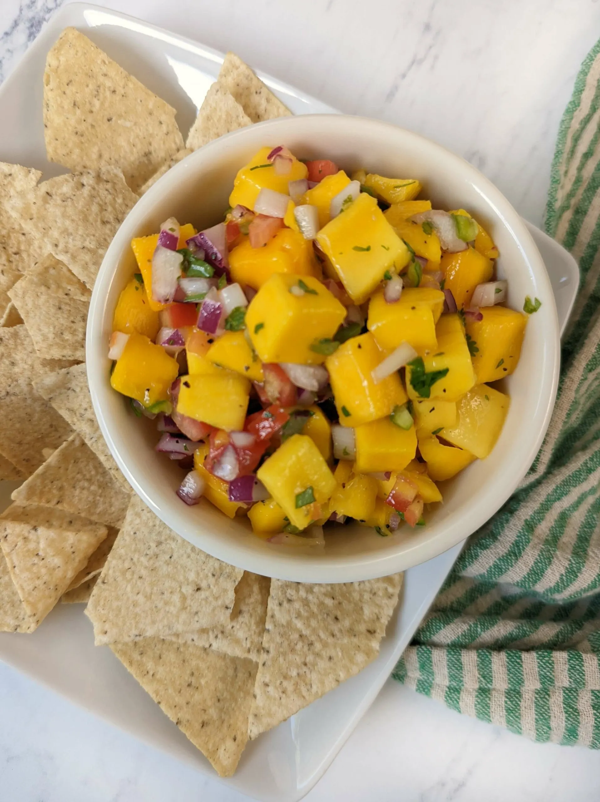 Mango salsa in a bowl next to chips.