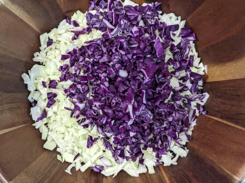 Purple cabbage added to a bowl.
