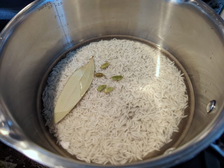 Add water, rice, cardamom pods, and salt to a sauce pan and bring it to a boil..
