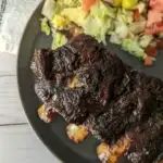 Beef ribs on a plate with salad.