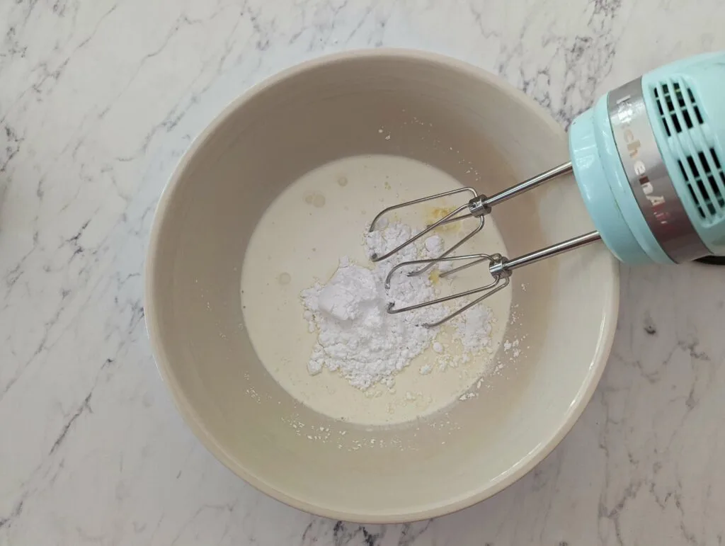 The ingredients for homemade whipped cream in a mixing bowl.