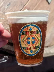 A hand holding a butterbeer drink from the Leaky Cauldron in New York.