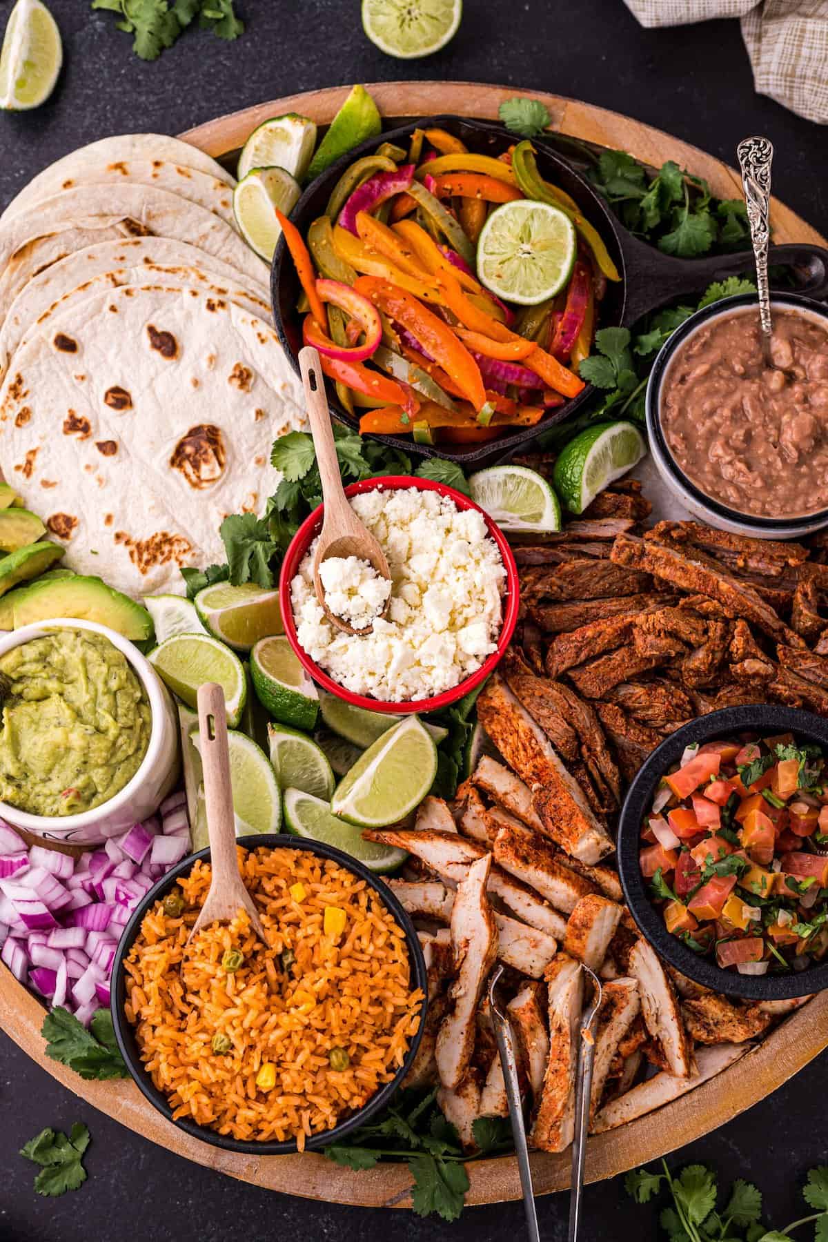 A table full of different kinds of fajitas and their toppings. 