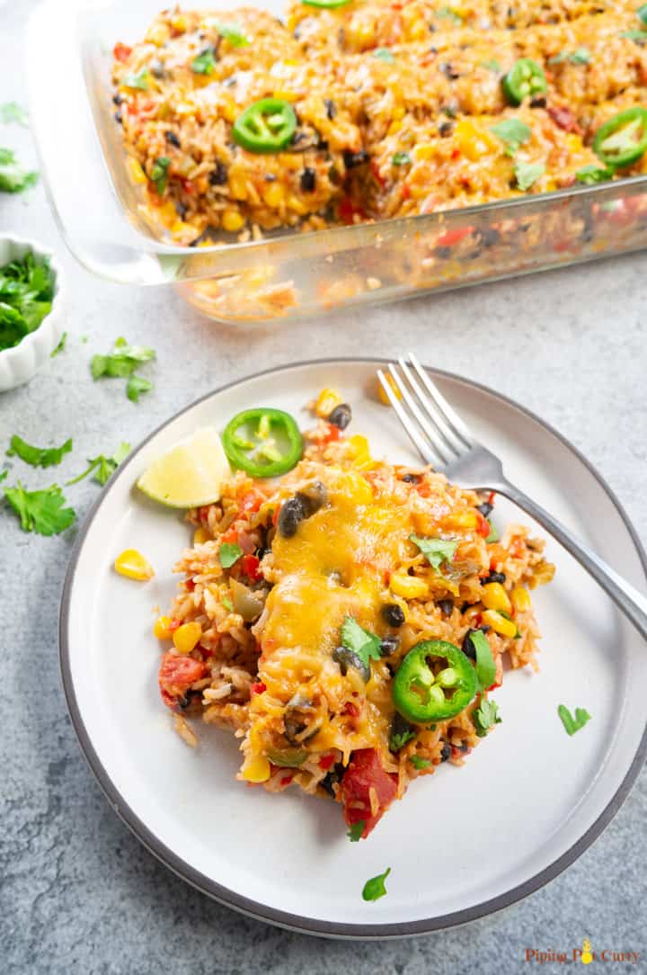 A serving of Mexican casserole with the casserole dish in the background. 
