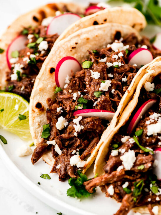 Barbacoa tacos with lime, onion, cotija cheese.