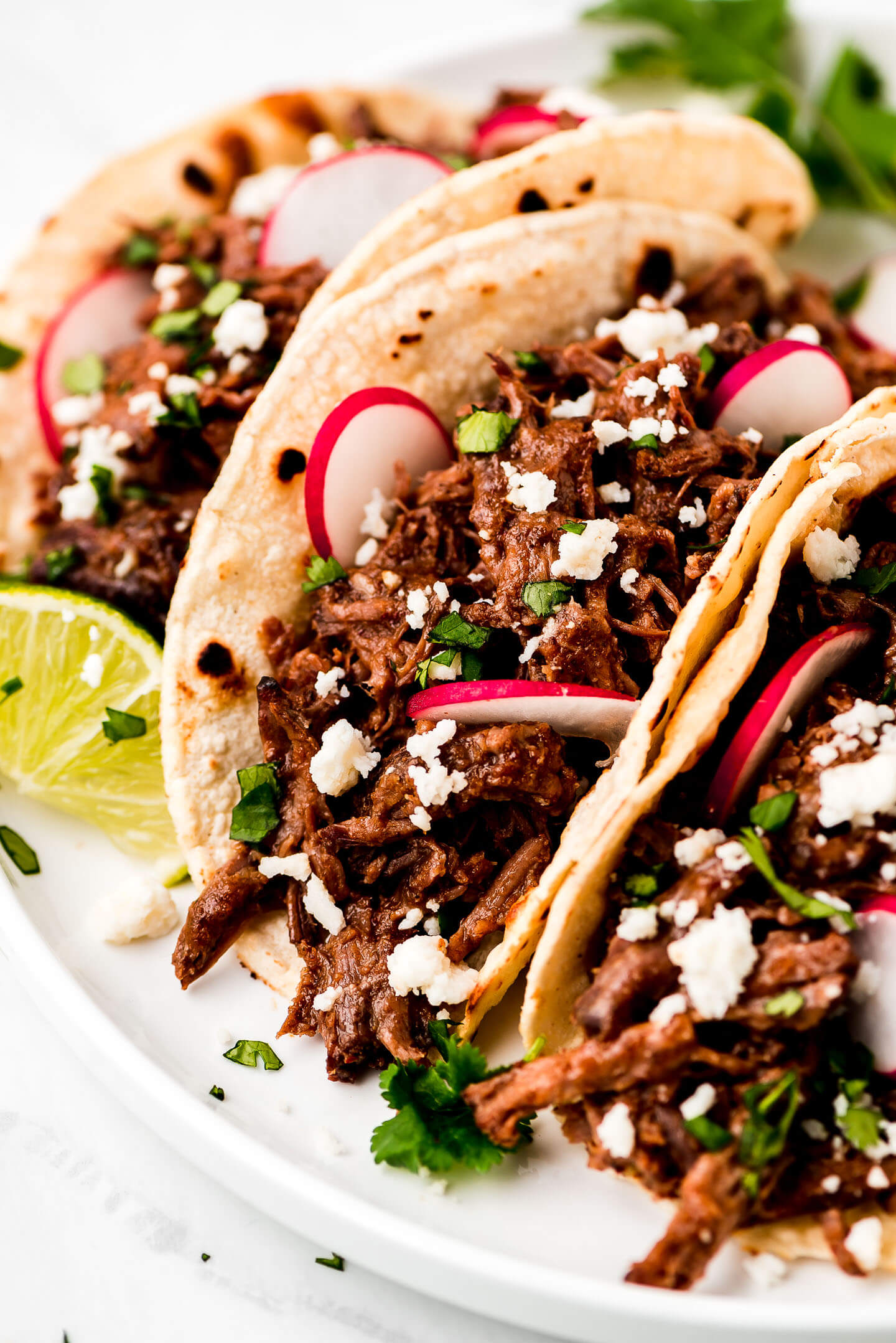 Barbacoa tacos with lime, onion, cotija cheese.