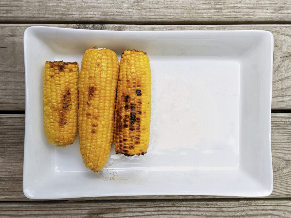 Grilled corn on the cob on a serving tray.