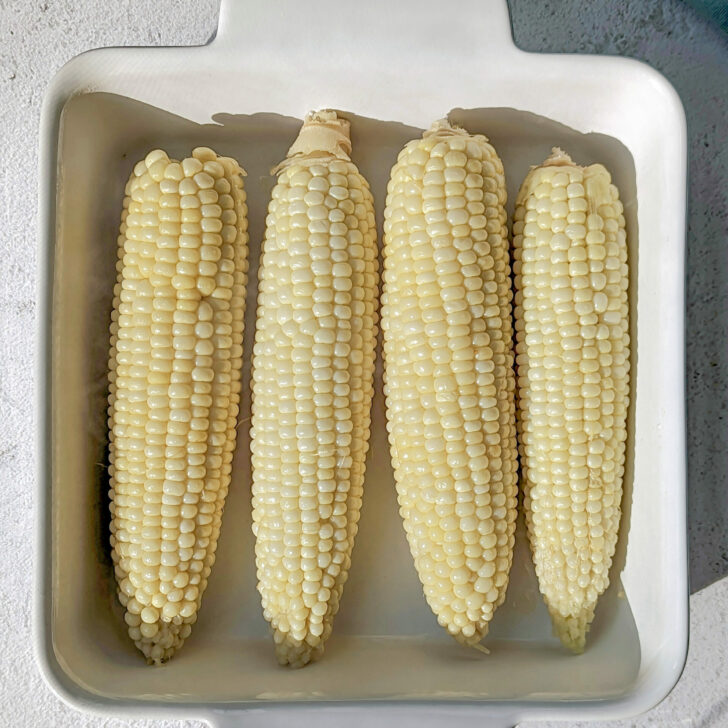 A close up of cook corn on the cob in a serving dish.