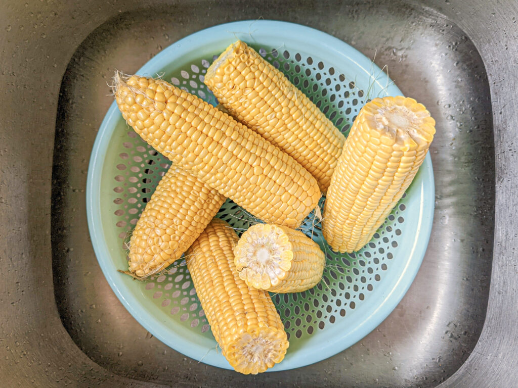 Peeled and washed the corn on the cob in a colander.