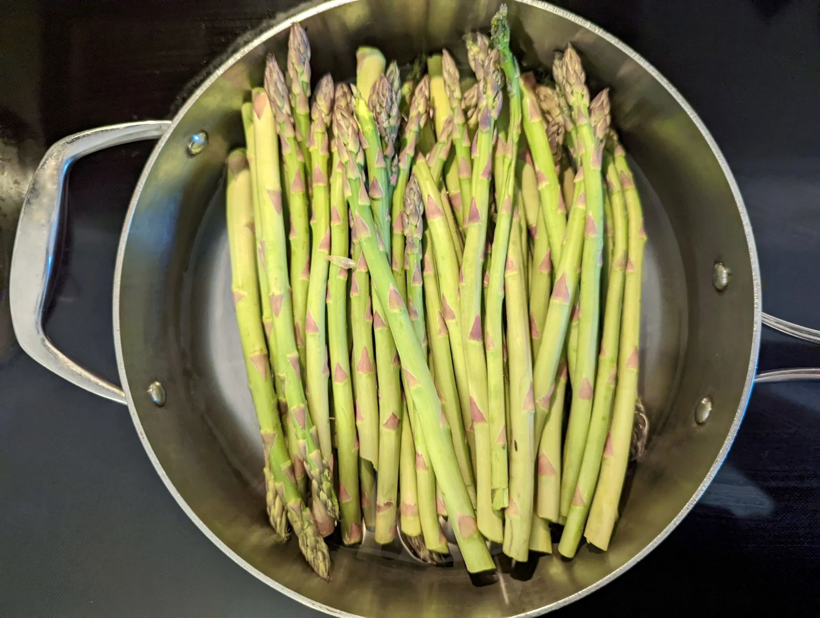 Asparagus and water in a saute pan. 