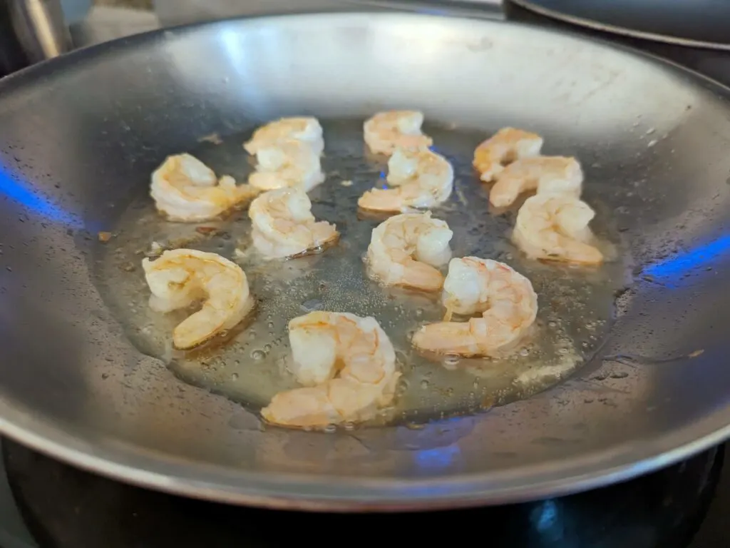 Searing shrimp in a pan.