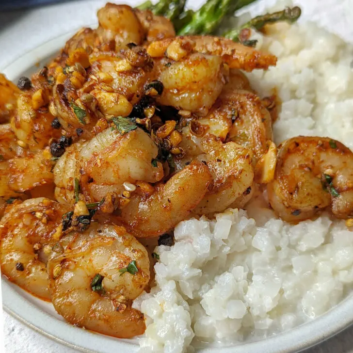 Pan seared shrimp on a plate with cauliflower rice and asparagus.