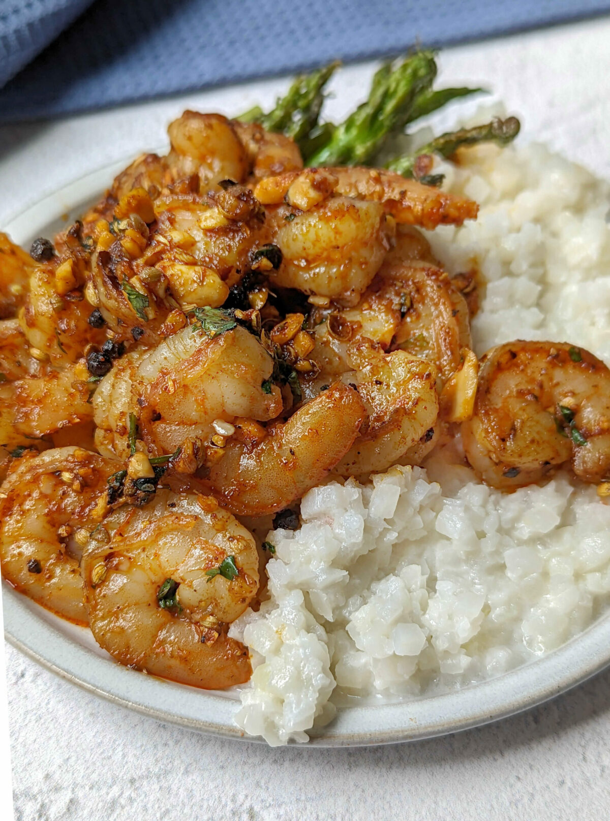 Pan seared shrimp on a plate with asparagus and cauliflower rice. 