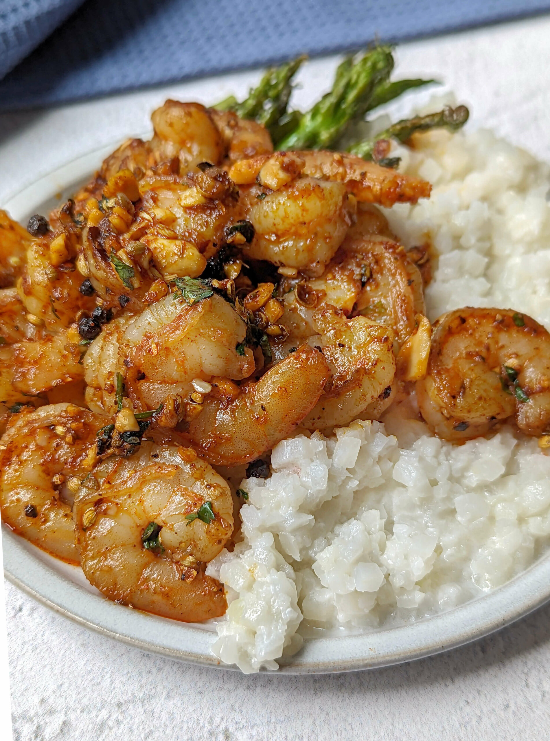 Pan seared shrimp on a plate with cauliflower rice and asparagus.