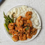 A plate of pan-seared shrimp over cauliflower rice.