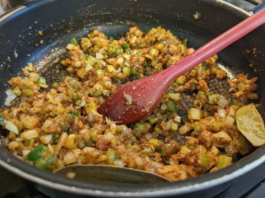 Cajun seasoning added to the vegetables cooking in a pan.