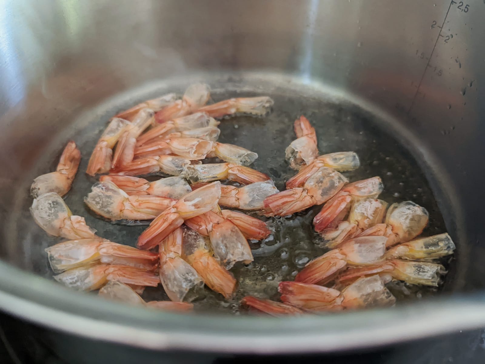 Shrimp tails searing in a pan to draw out the flavor.