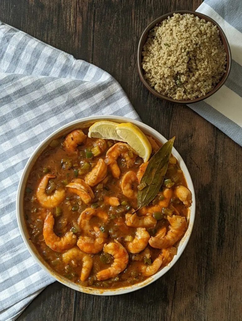 Shrimp étouffée in a serving dish with a side of quinoa in the background.