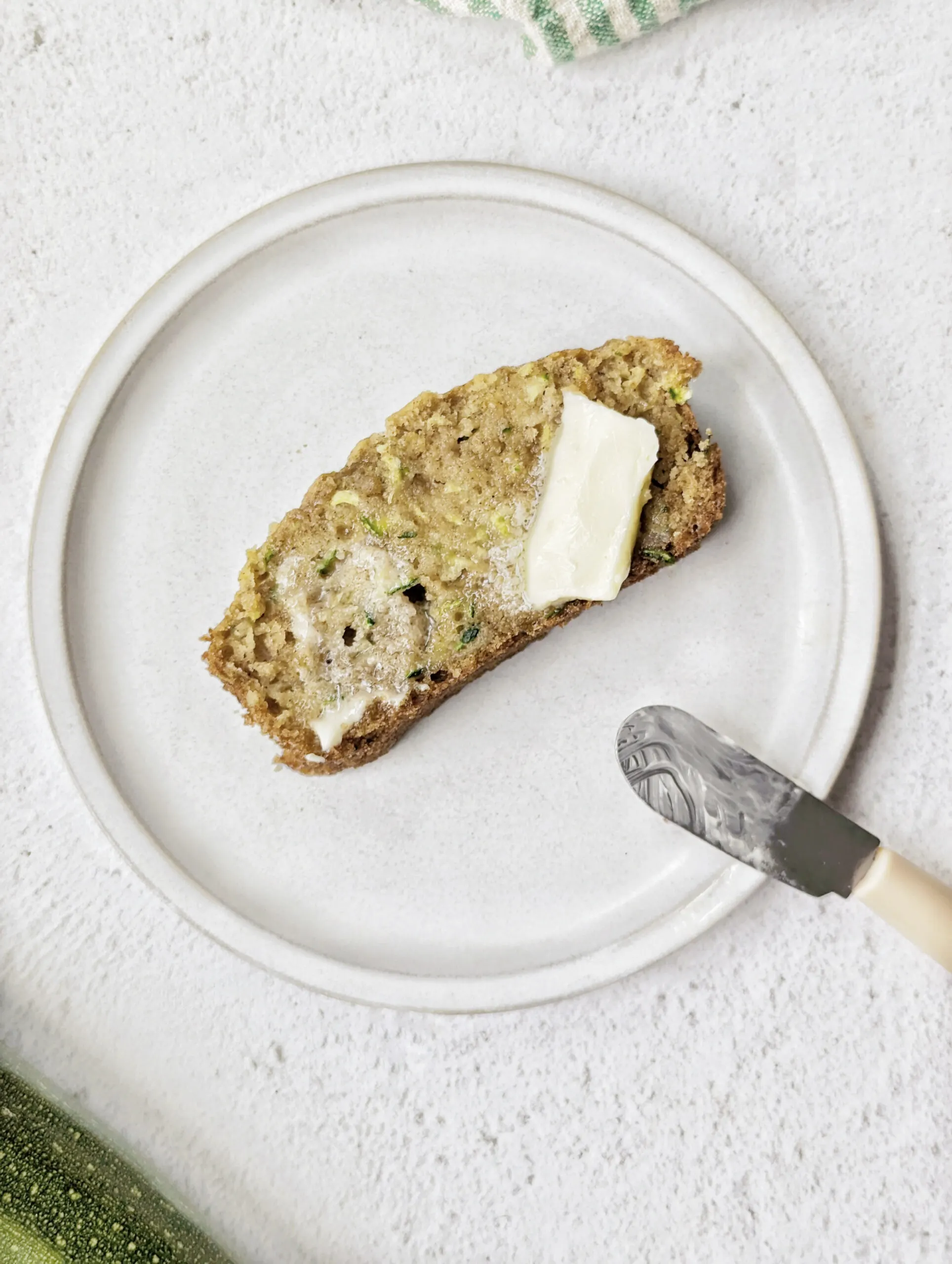 A slice of zucchini bread coated with butter.