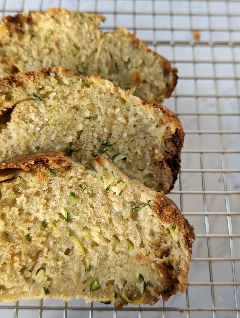 Sliced zucchini bread on a cooling rack.