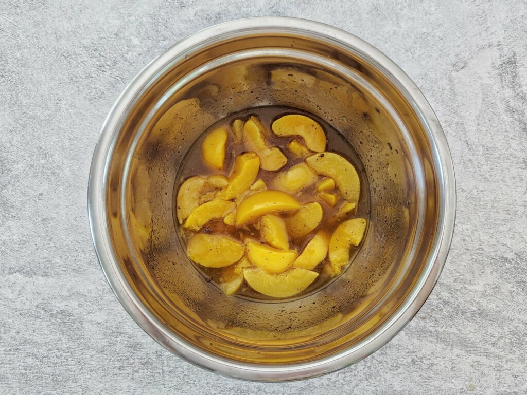 Peaches in a bowl with lemon juice, nut meg, and brown sugar.