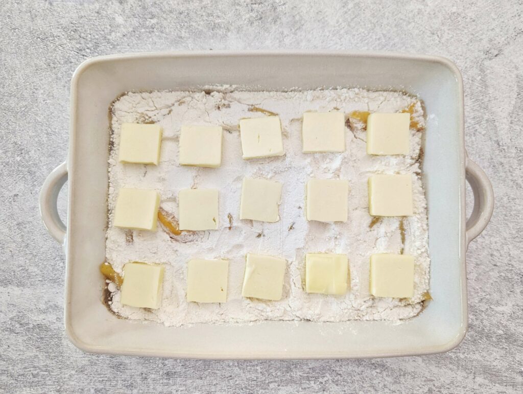 Tabs of butter lined up on the cake mix.
