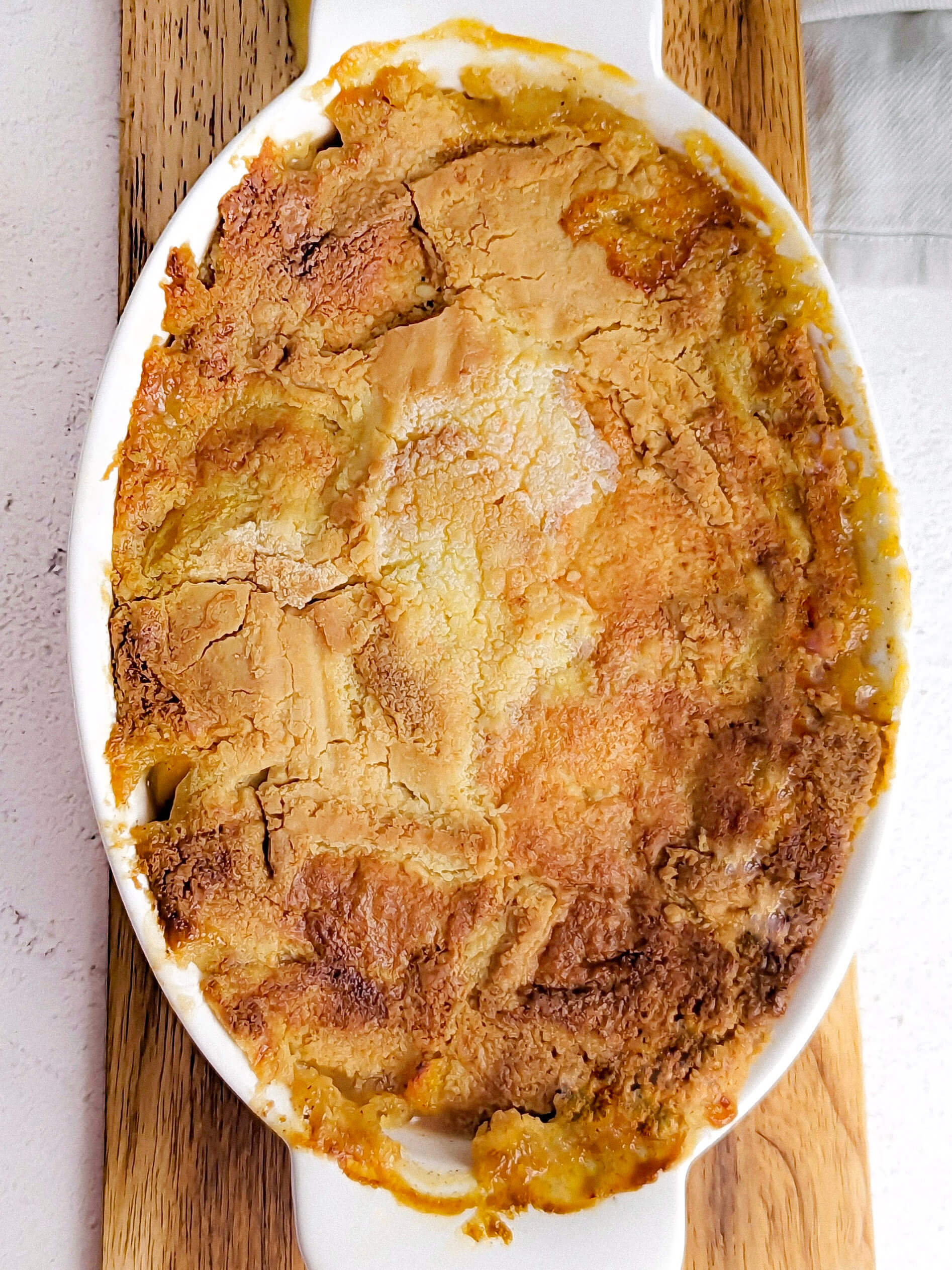 Easy Peach Cobbler with Cake Mix in a serving dish surrounded by peaches.